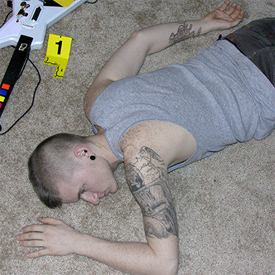 Young man with a mohawk and tattoos lying face down on a carpeted floor