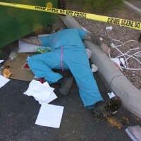 Man lying on his back next to a dumpster