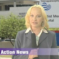 TV reporter holding a microphone and standing in front of a hospital