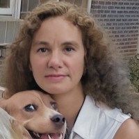 Woman with long dark curly hair holding a dog
