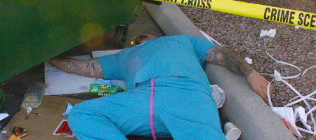 Man lying dead next to a dumpster