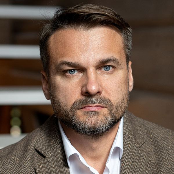 Serious man with brown hair and graying beard and mustache